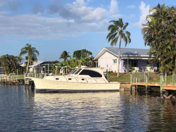 Mainship 34 PILOT Rumrunner II 2005 Mainship 34 PILOT Rumrunner II docked by a waterfront home with palm trees.