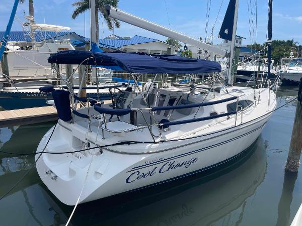 Catalina 309 2006 Hunter 309 sailboat docked, featuring blue canopy and sleek design.