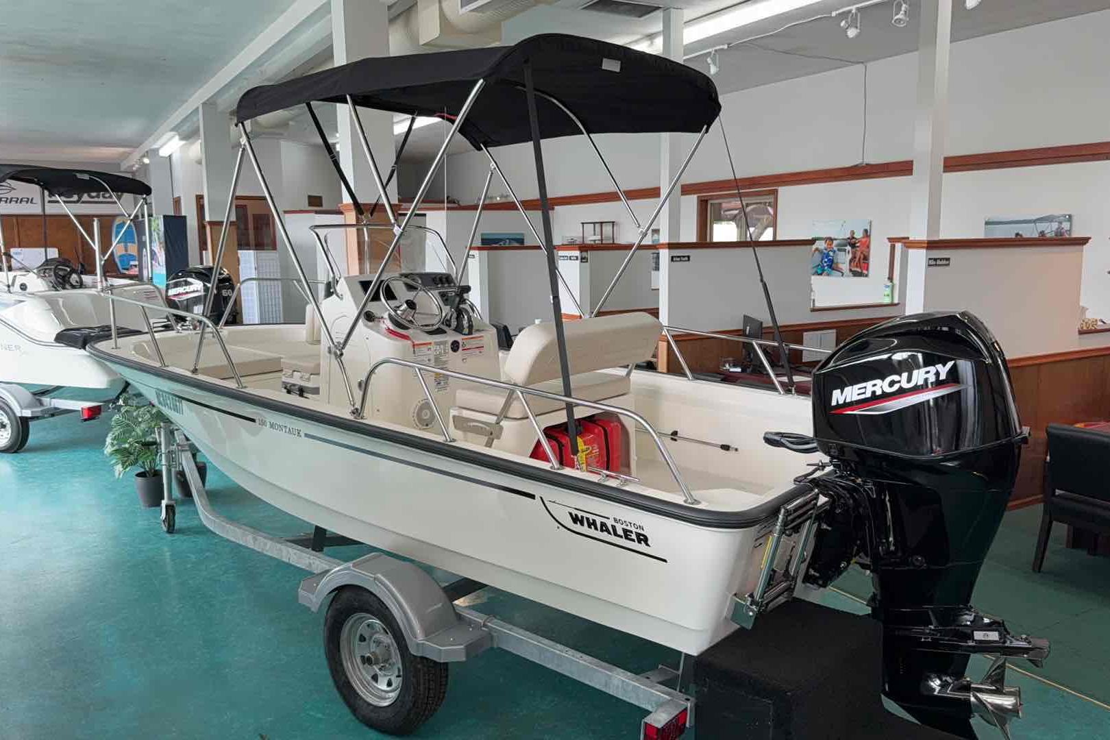 Boston Whaler 150 Montauk 2025 Boston Whaler 15 Montauk boat with Mercury engine displayed indoors.