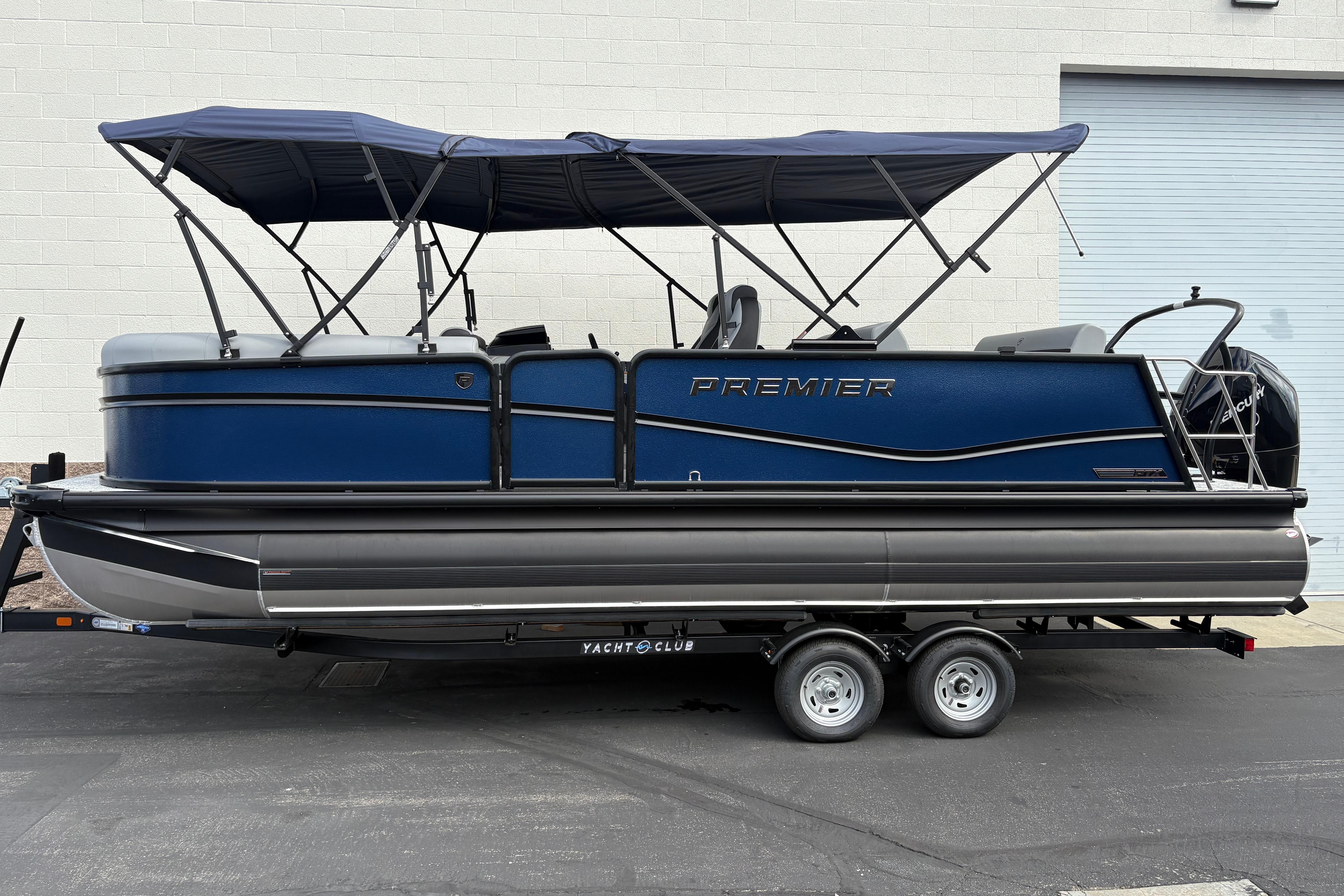 Premier 230 Sunsation RL 2026 Premier 230 Sunsation RL pontoon boat with blue canopy on trailer.