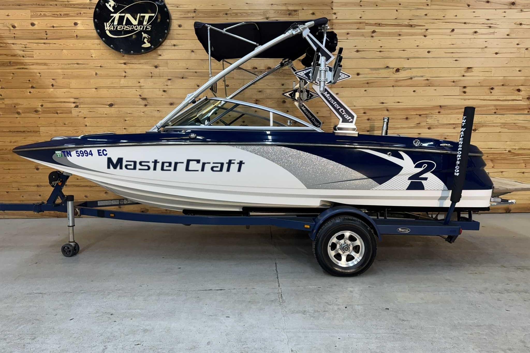 MasterCraft X2 2011 MasterCraft X2 boat on trailer in showroom with wooden wall background.