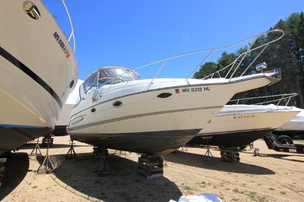 Maxum 2800 SCR 1999 Maxum 2800 SCR boat on stands, surrounded by other boats, under clear blue sky.