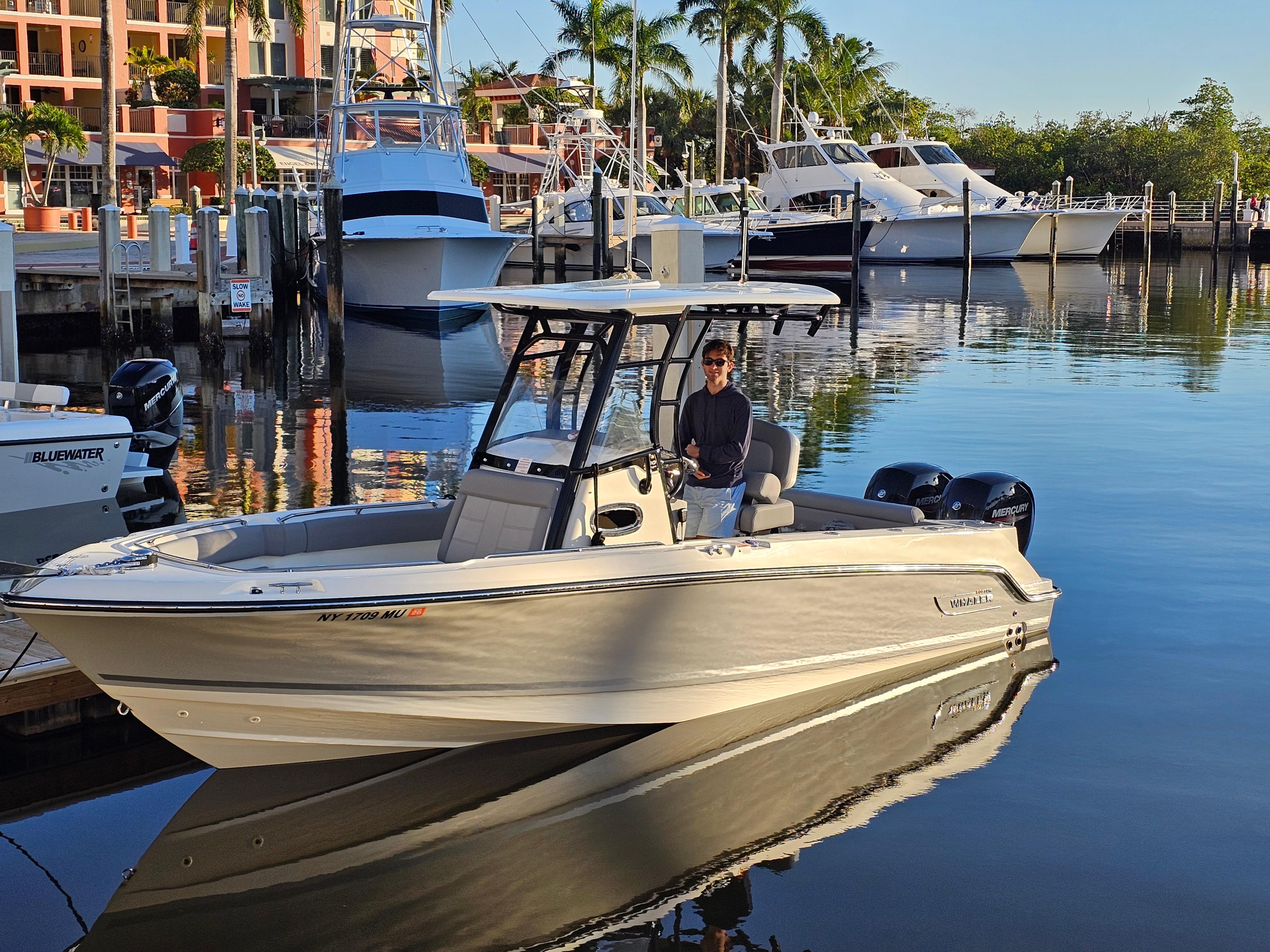 Boston Whaler Outrage 230 2023 Boston Whaler Outrage 230 boat docked in a marina with palm trees.