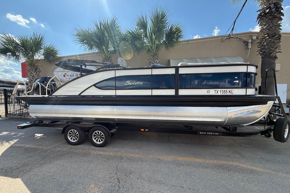 Barletta L23UC 2021 Barletta L23UC pontoon boat on trailer, parked outdoors under palm trees.