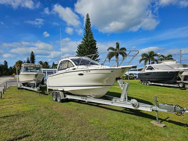 Cutwater C-24 Coupe 2021 Cutwater C-24 Coupe boat on trailer, parked on grass under blue sky.