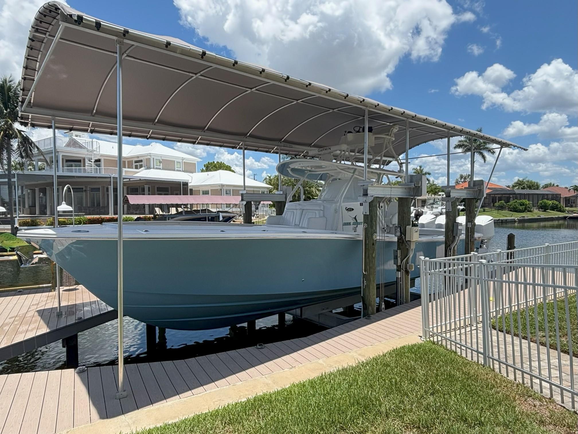 Regulator 41 2017 Regulator 41 boat docked under canopy, sunny day, waterfront homes in background.