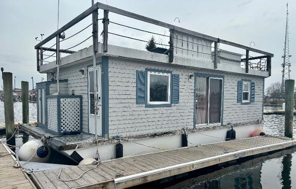 Custom Houseboat Custom 1990 houseboat docked, featuring blue shutters and a rooftop deck.