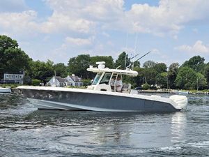 Boston Whaler OUTRAGE 330 2017 Boston Whaler 330 Outrage boat on calm water, surrounded by trees and houses.