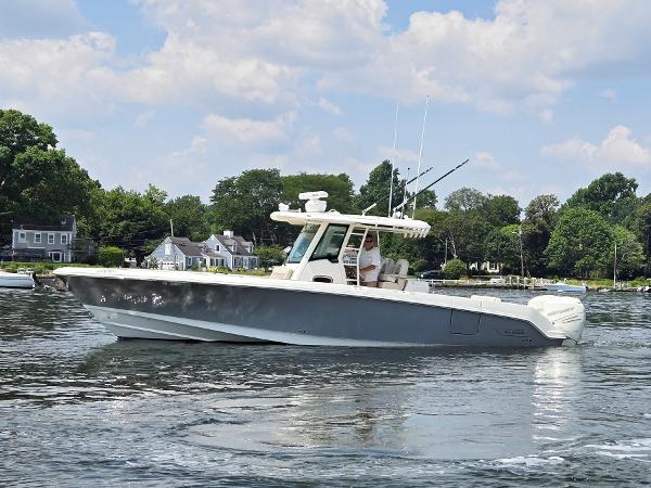 Boston Whaler OUTRAGE 330 2017 Boston Whaler 330 Outrage boat on calm water, surrounded by trees and houses.