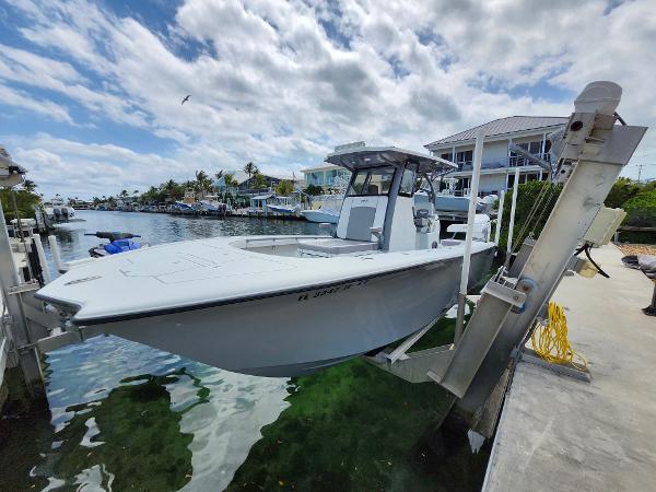 Costa Custom Boats 264 HC 2022 Costa Custom Boats 264 HC on lift by waterfront homes under cloudy sky.