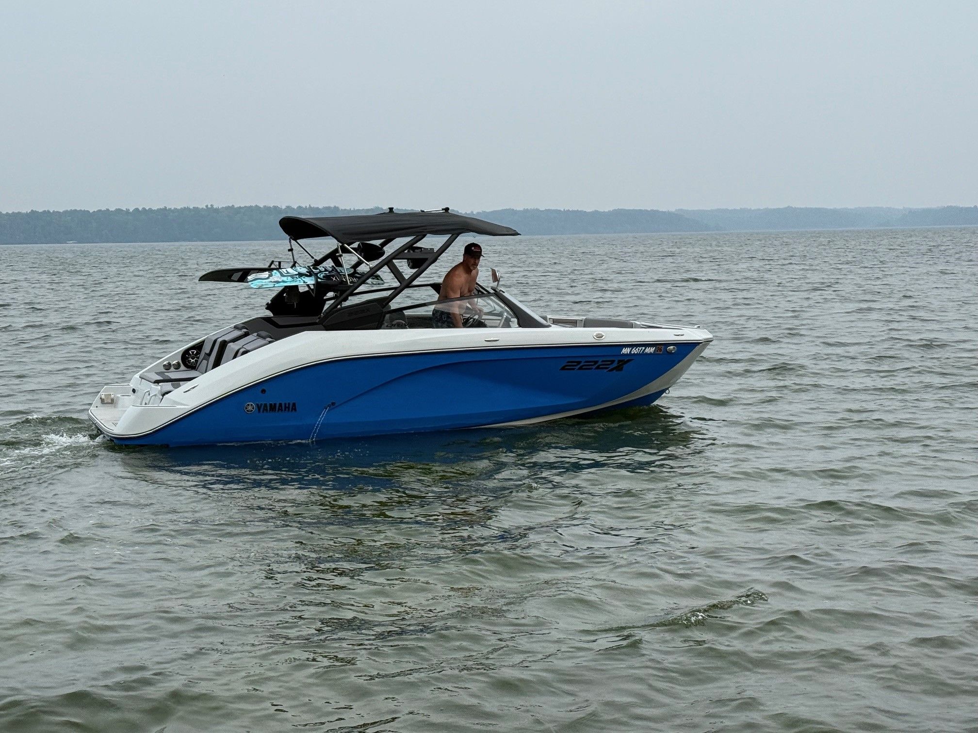 Yamaha Boats 222XD 2024 Yamaha Boats 222XD on a calm lake, featuring sleek blue and white design.