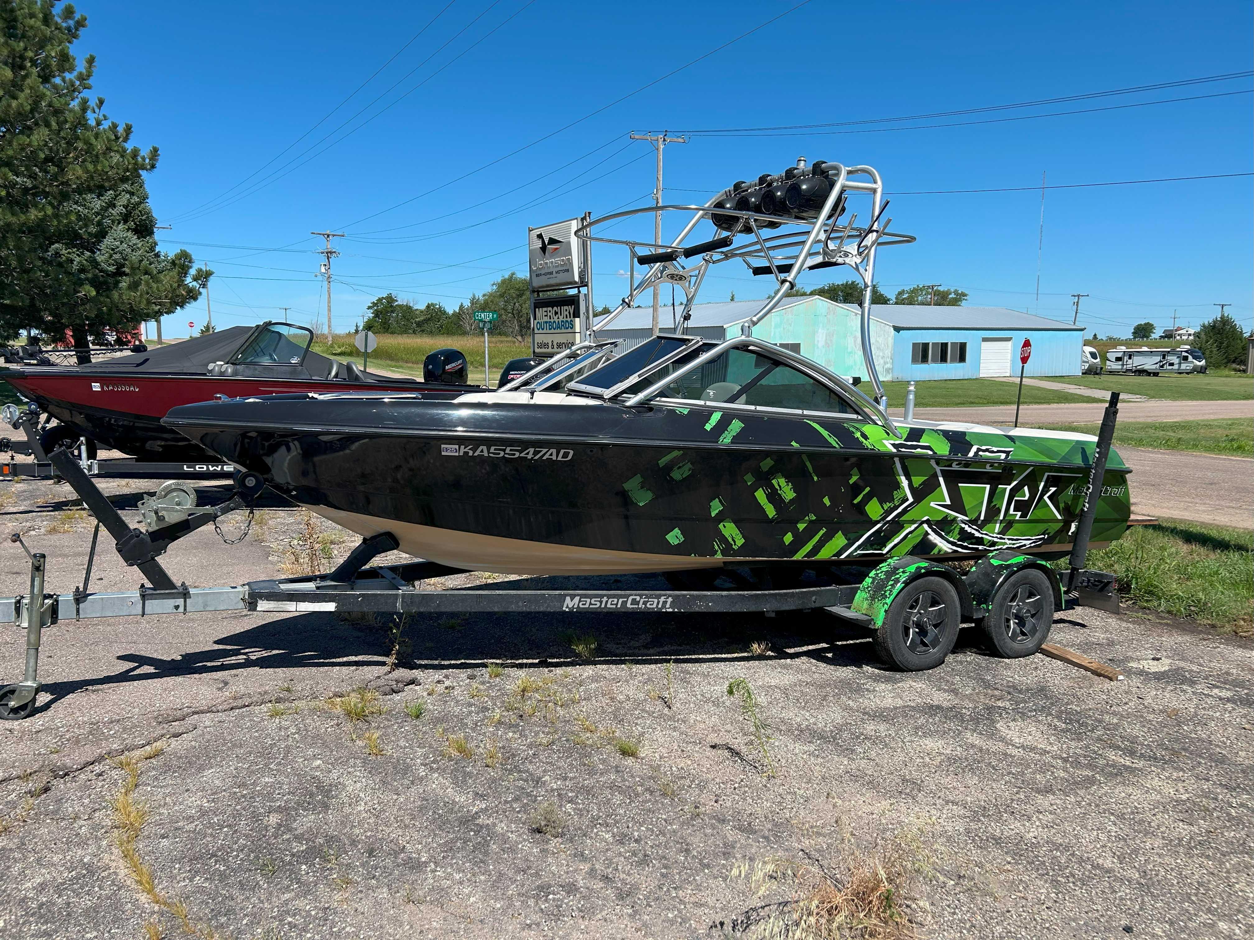 MasterCraft XStar 2002 MasterCraft XStar boat with green and black design on a trailer, parked outdoors.