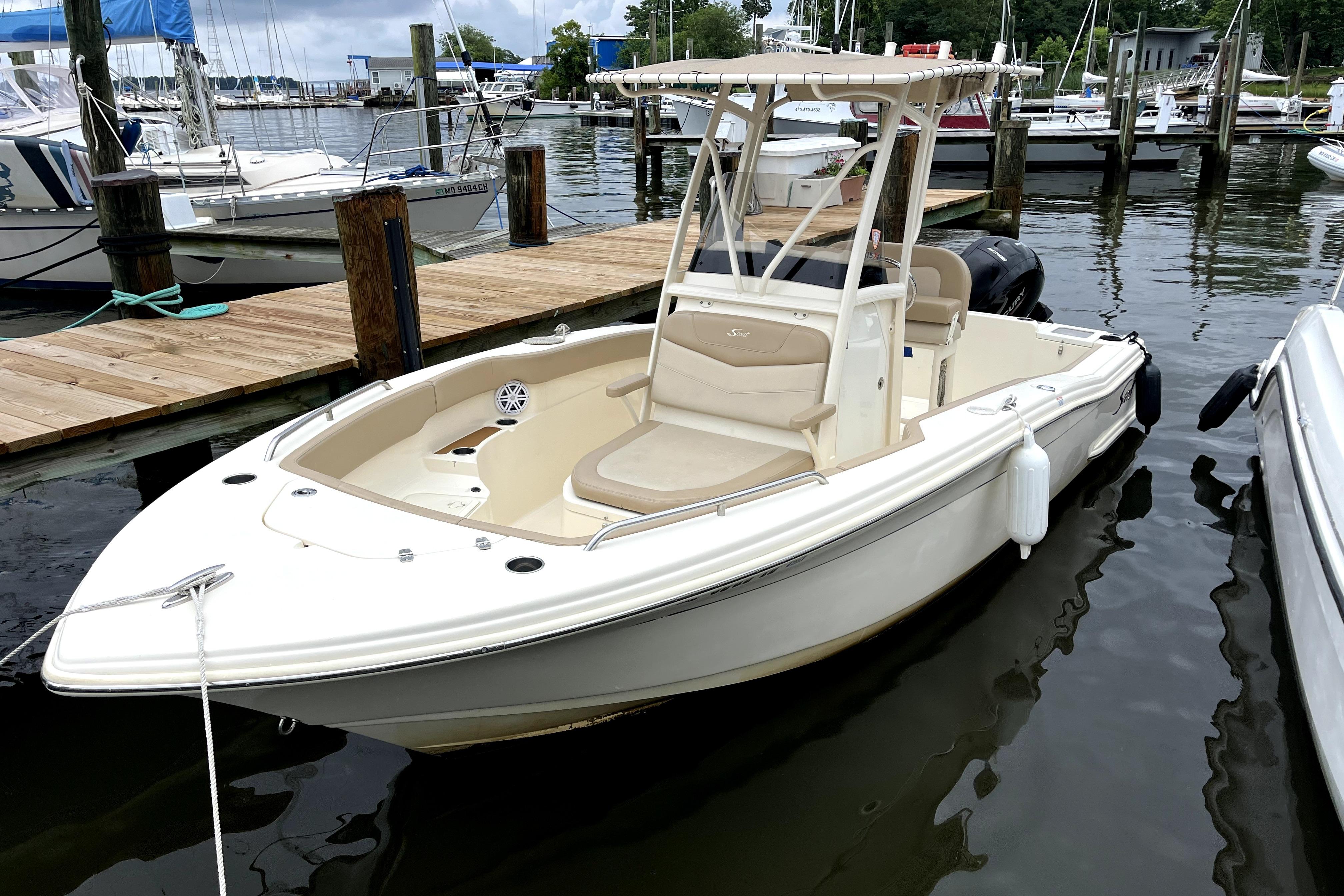 Scout 215 XSF 2023 Scout 215 XSF boat docked at marina, featuring sleek design and spacious seating.