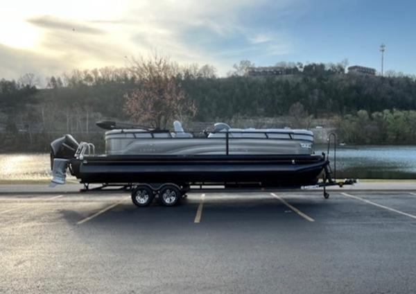 Regency 250 LE3 2024 Regency 250 LE3 pontoon boat on trailer by a scenic lake.