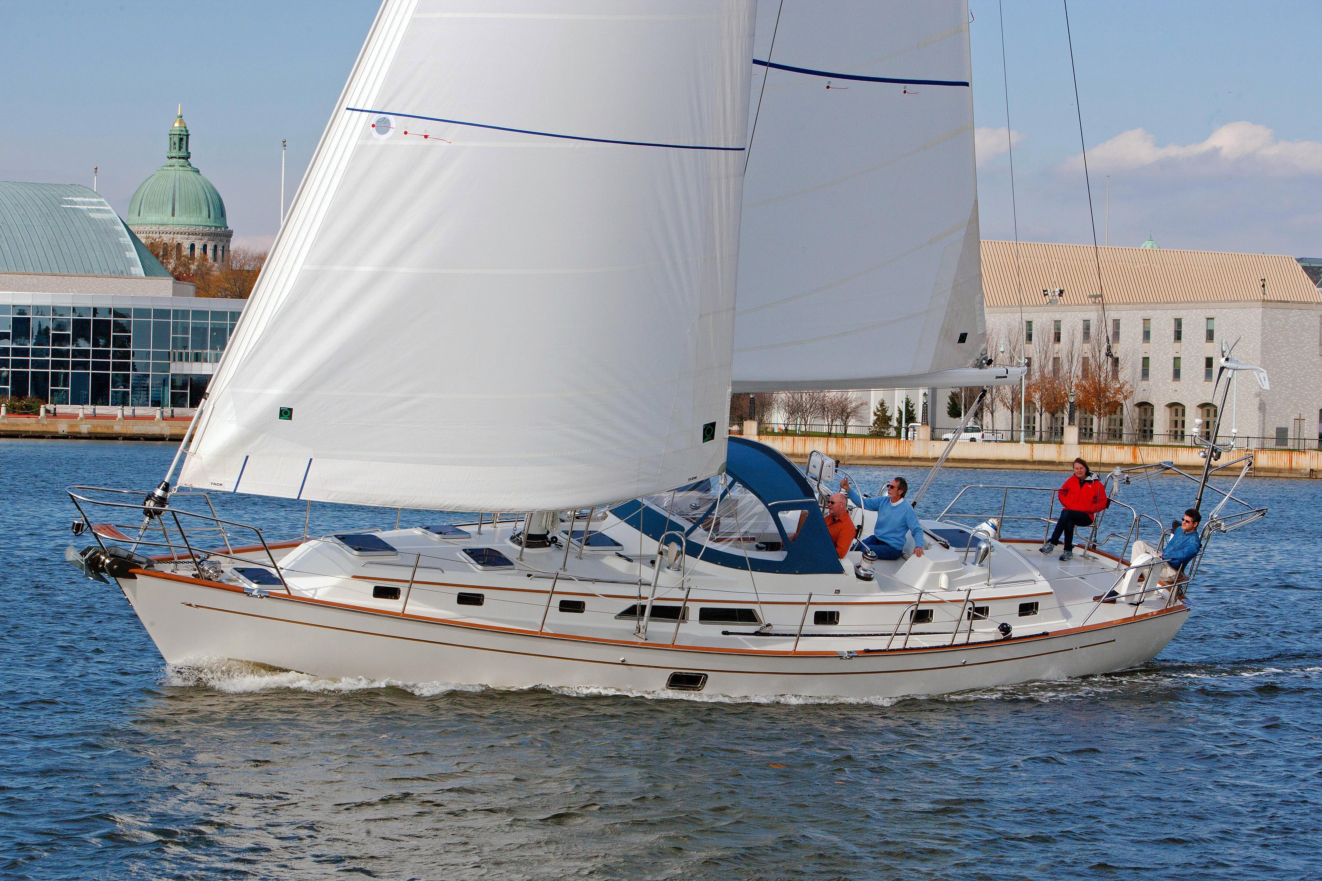 Passport 470 Center Cockpit Sailing the 2013 Passport 470 Center Cockpit yacht on a sunny day near waterfront buildings.