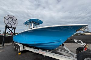 Sea Hunt Gamefish 27 Forward Seating 2020 Sea Hunt Gamefish 27 boat on trailer, vibrant blue hull, overcast sky.