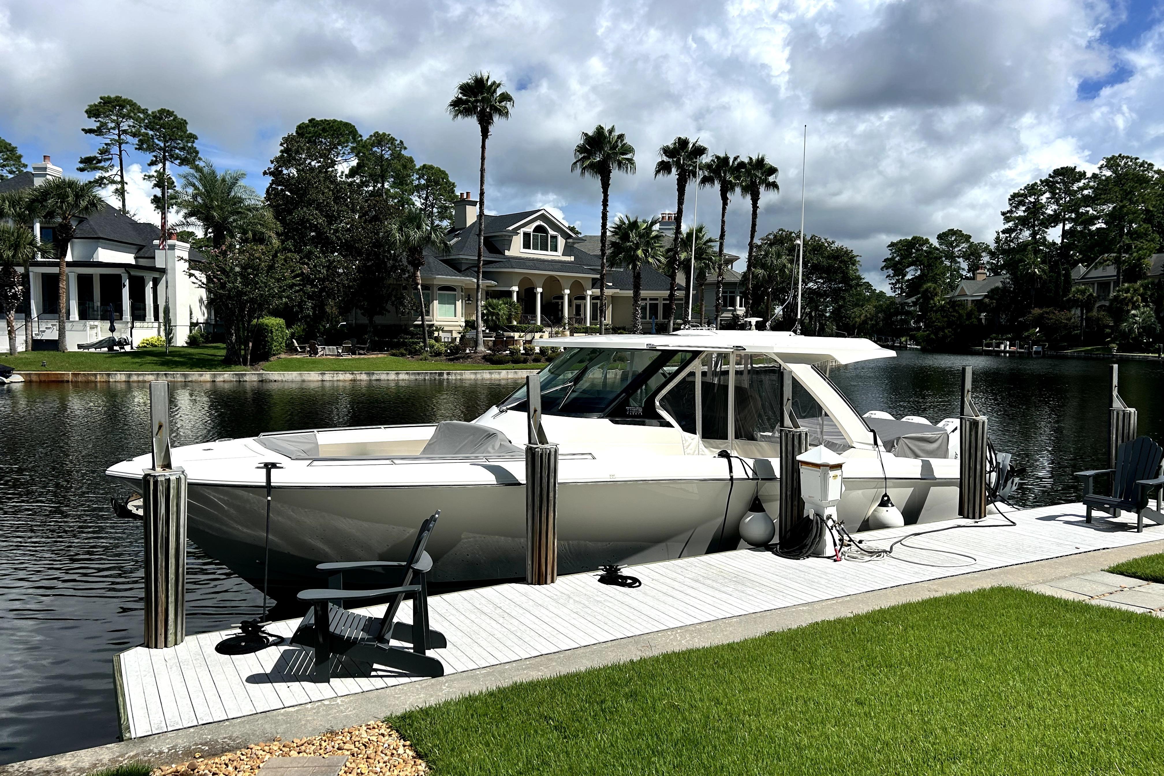 Tiara Yachts 38 LS 2023 Tiara Yachts 38 LS docked by a scenic waterfront with palm trees.