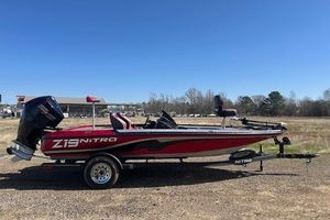 Nitro Z19 2025 Nitro Z19 boat in red, parked on a trailer in an open field.