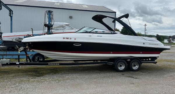 Rinker QX29 BR 2018 Rinker QX29 BR boat on a trailer in a marina.