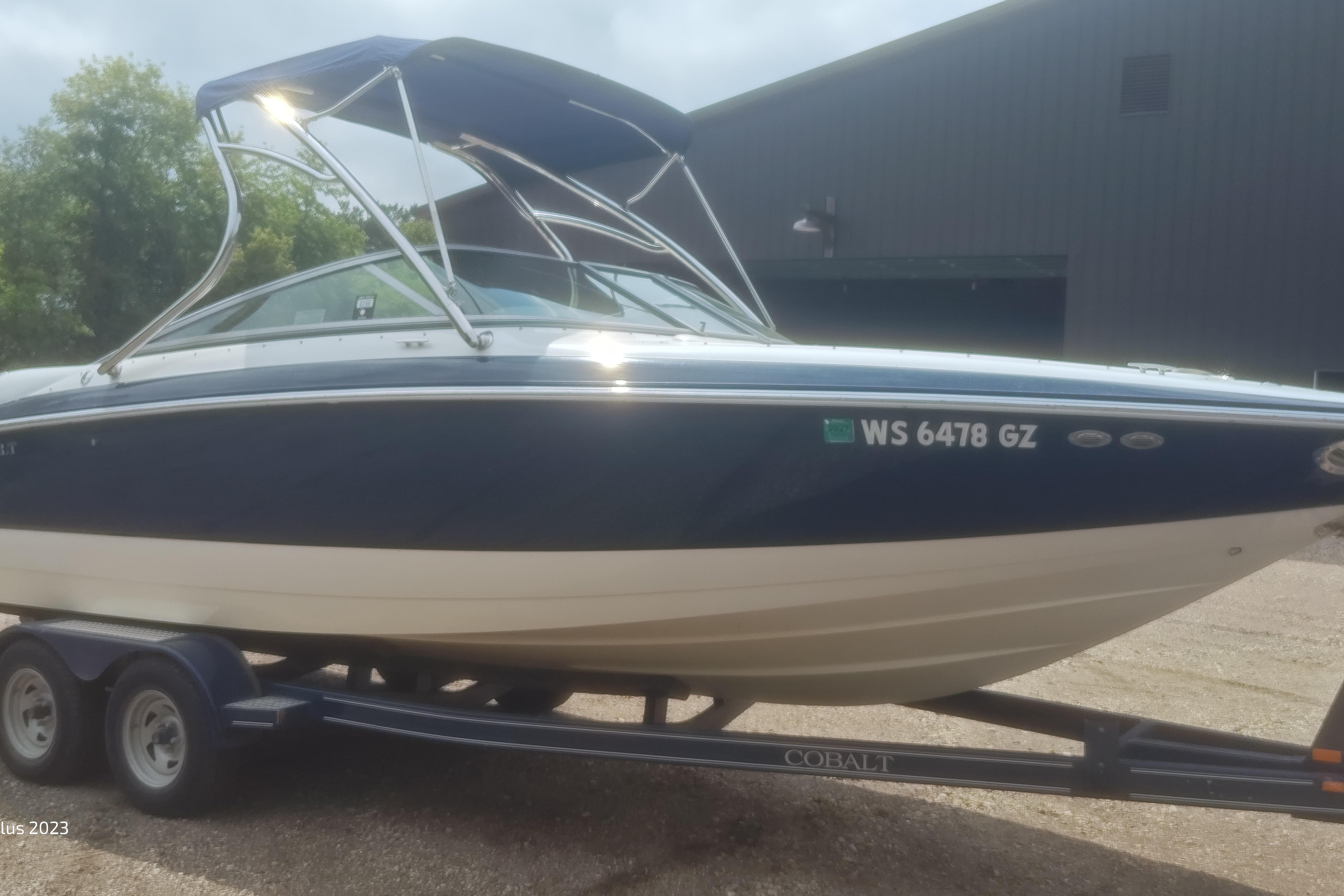 Cobalt 240 2006 Cobalt 240 boat on trailer, blue and white, parked outdoors.