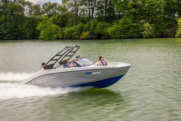 Yamaha Boats AR220 2026 Yamaha Boats AR220 speeding on a lake with lush green trees in the background.