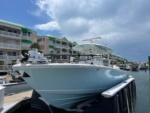 Cobia 320 Center Console 2019 Cobia 320 Center Console boat docked at marina with waterfront condos in background.