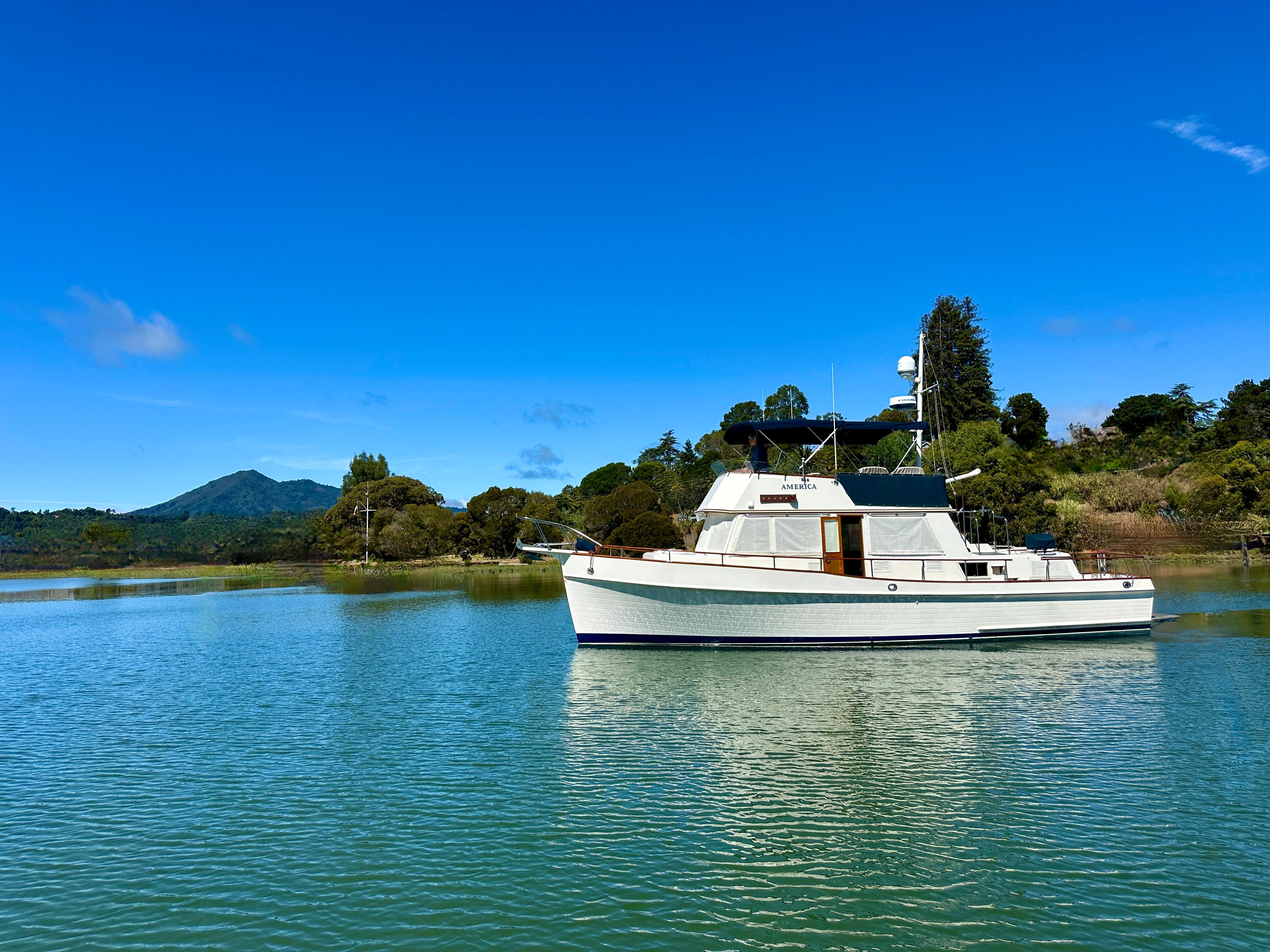 Grand Banks 42 Classic 1989 Grand Banks 42 Classic yacht on serene water with lush green backdrop.