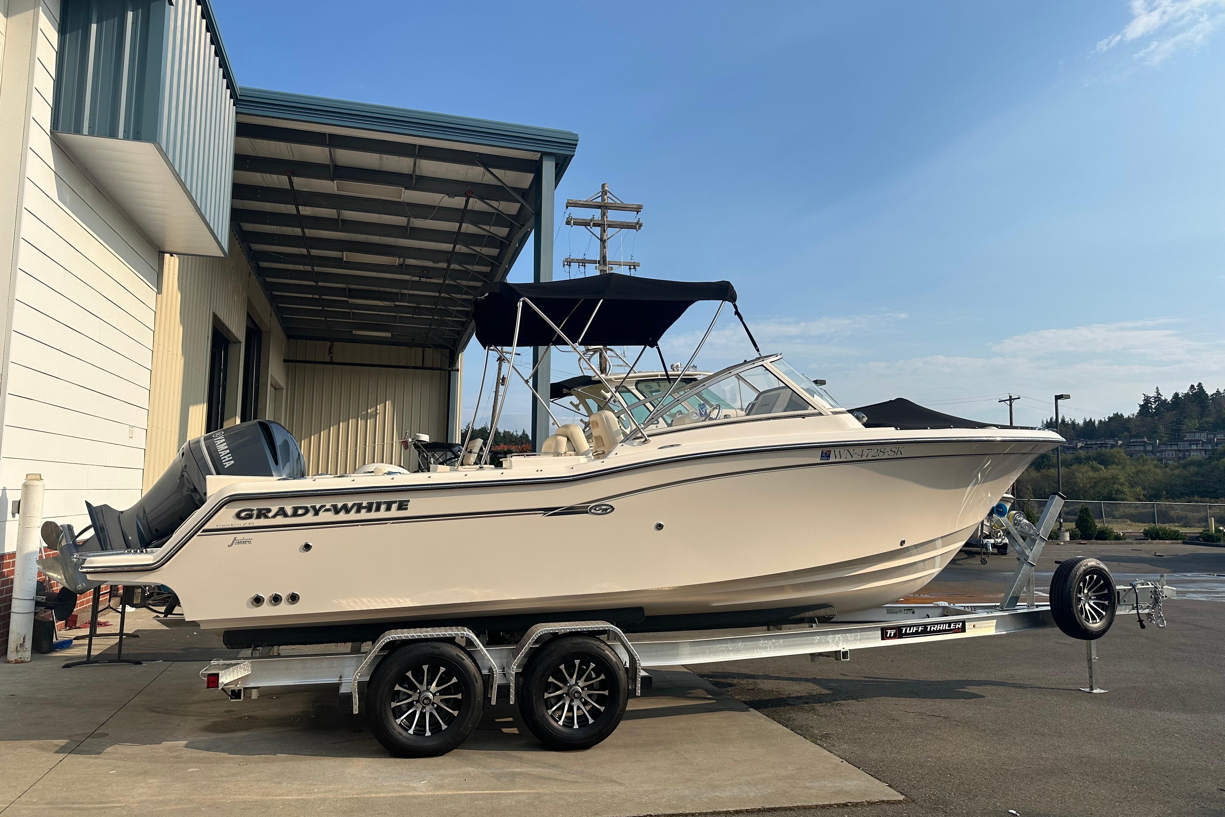 Grady-White Freedom 235 2017 Grady-White 235 boat on trailer, parked outside a building.