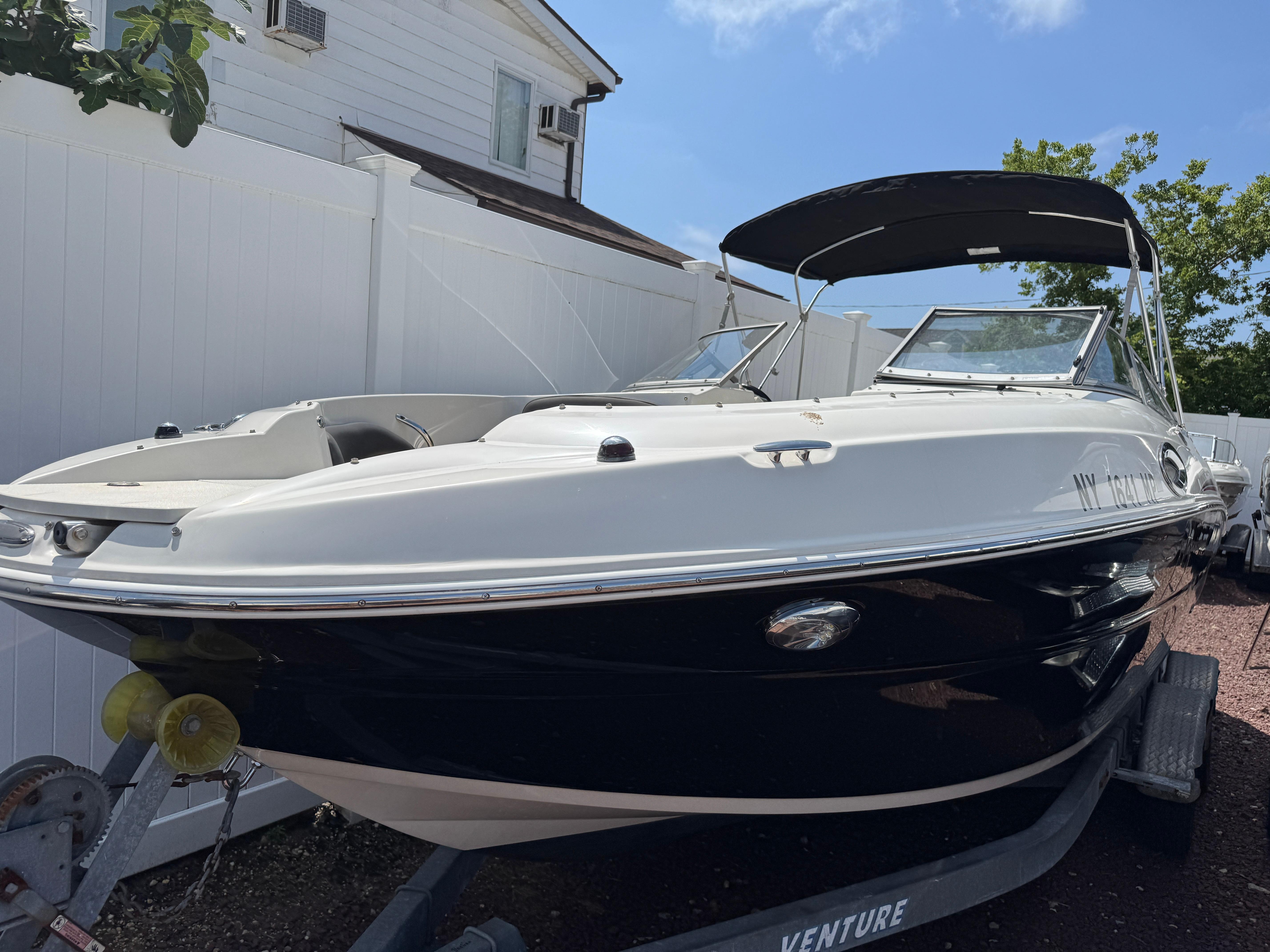 Stingray 234 LR 2018 Stingray 234 LR boat on trailer, parked outdoors near white fence.