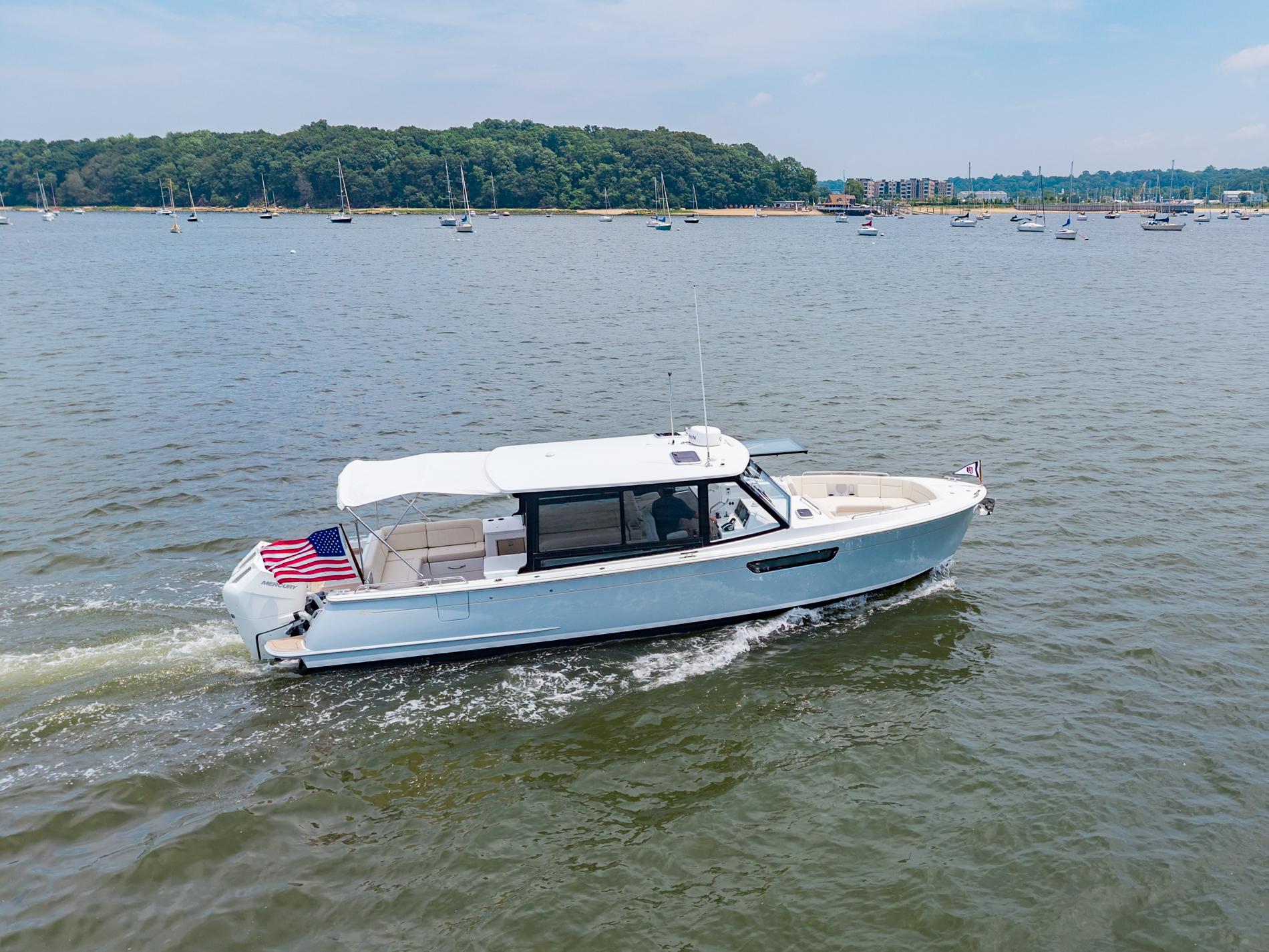 MJM 3 2025 MJM 3 boat cruising on a scenic lake with lush green shoreline.