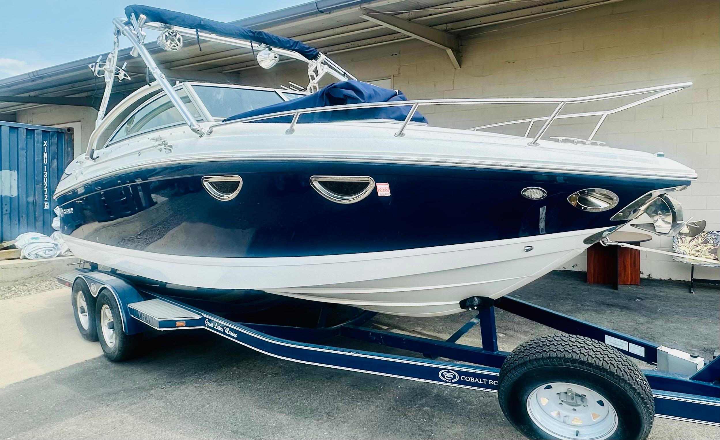 Cobalt 243 2012 Cobalt 243 boat on trailer, blue and white, parked outdoors.