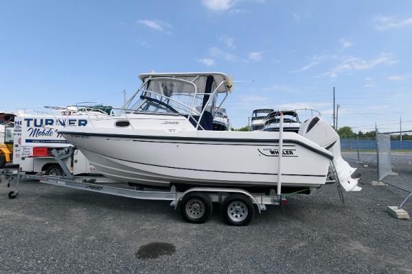 Boston Whaler 23 Conquest 2001 Boston Whaler 23 Conquest boat on trailer, parked outdoors under clear sky.