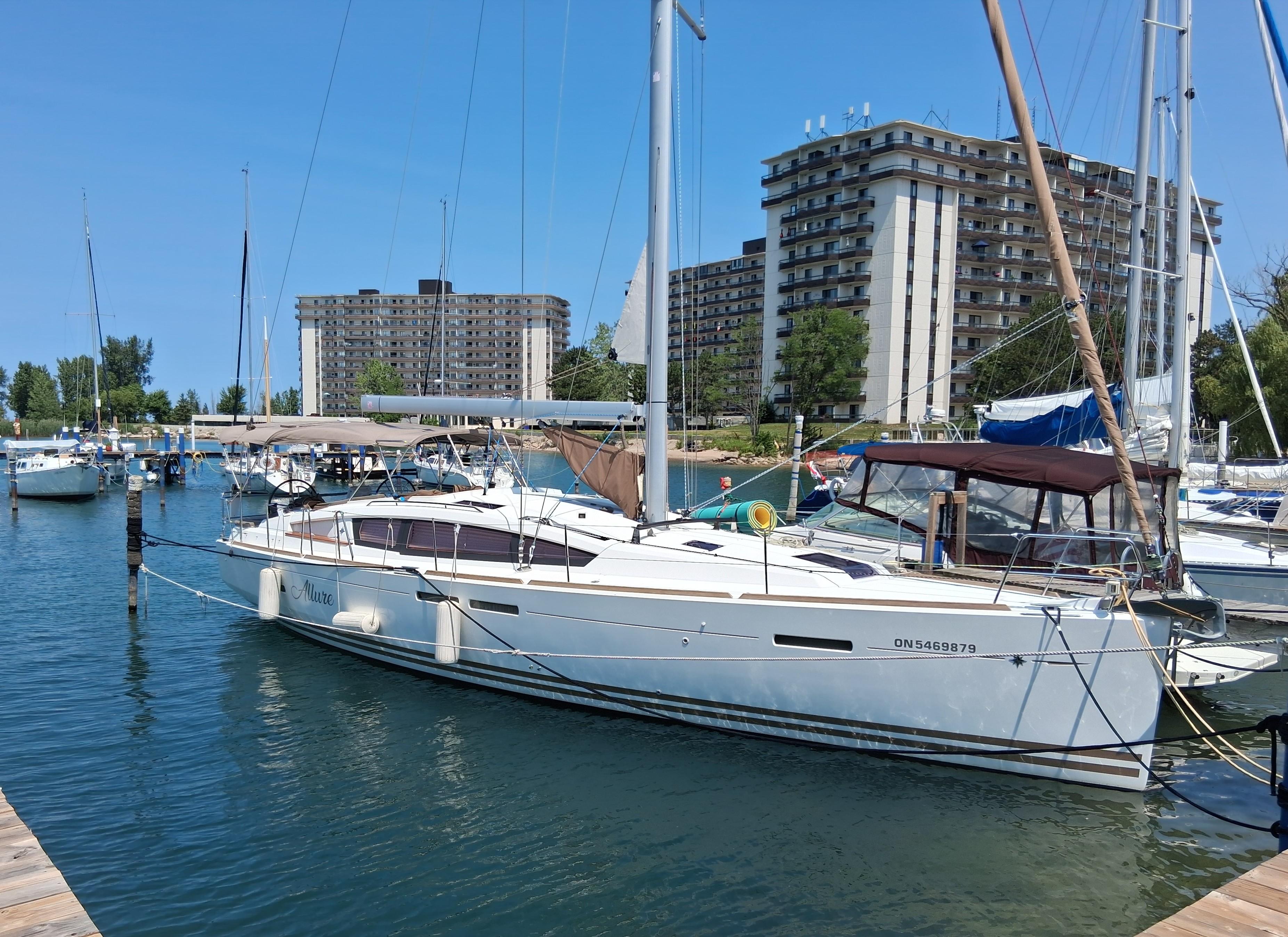 Jeanneau Sun Odyssey 44 DS 2016 Jeanneau Sun Odyssey 44 DS sailboat docked in marina, with buildings in background.