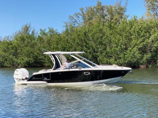 Chaparral 280 OSX 2021 Chaparral 280 OSX boat cruising on a calm river with lush greenery.