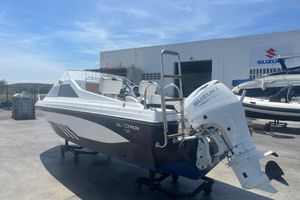 Glastron Medium day 1991 Glastron Medium Day boat with Suzuki outboard motor, parked outdoors near a Suzuki dealership.