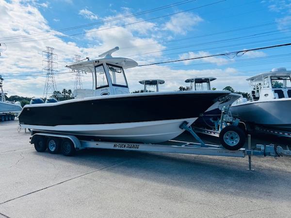 Sea Hunt Gamefish 27 Coffin Box 2019 Sea Hunt Gamefish 27 boat on trailer, parked outdoors under blue sky.