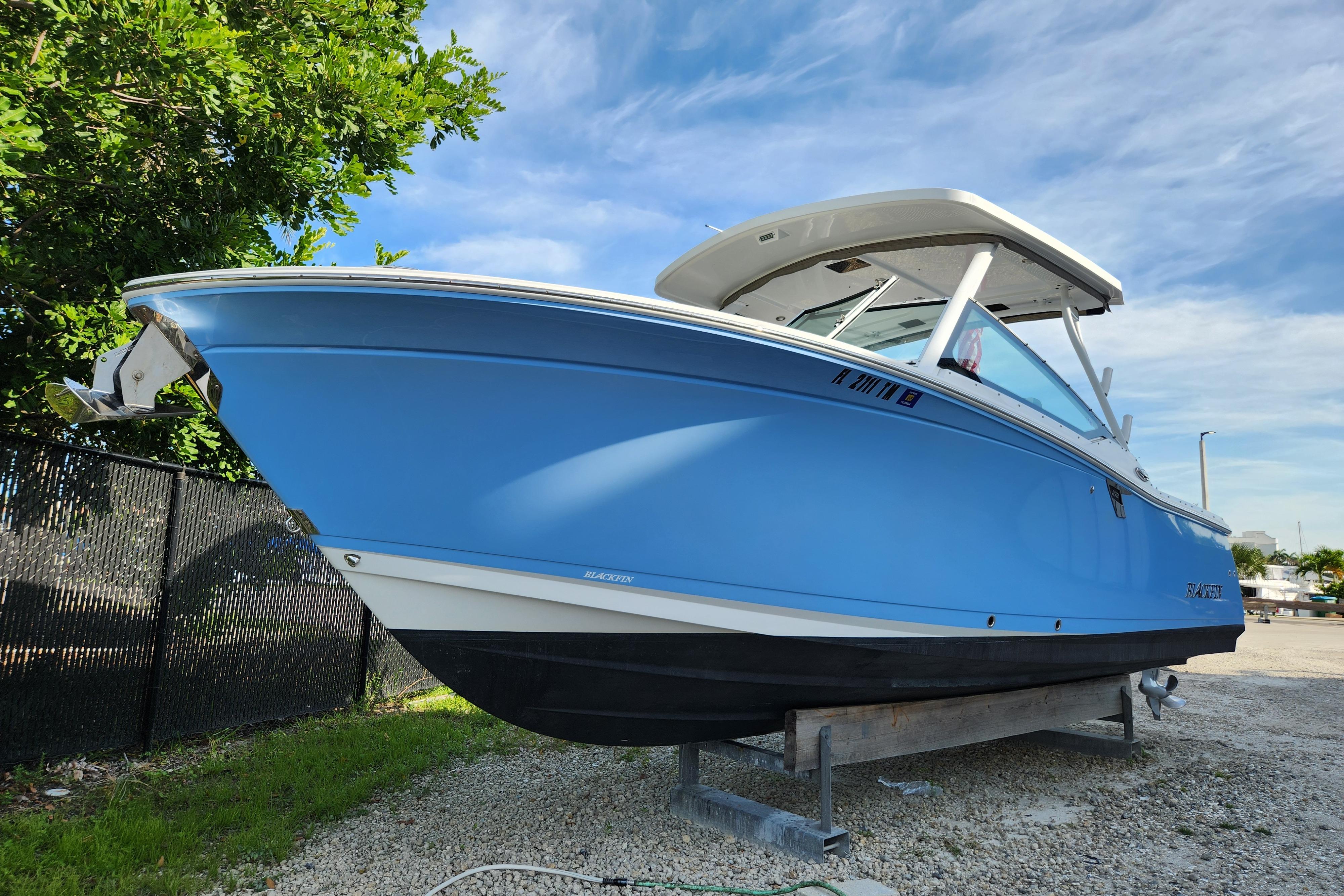 Blackfin 272 DC 2020 Blackfin 272 DC boat in blue, parked on gravel with a clear sky background.