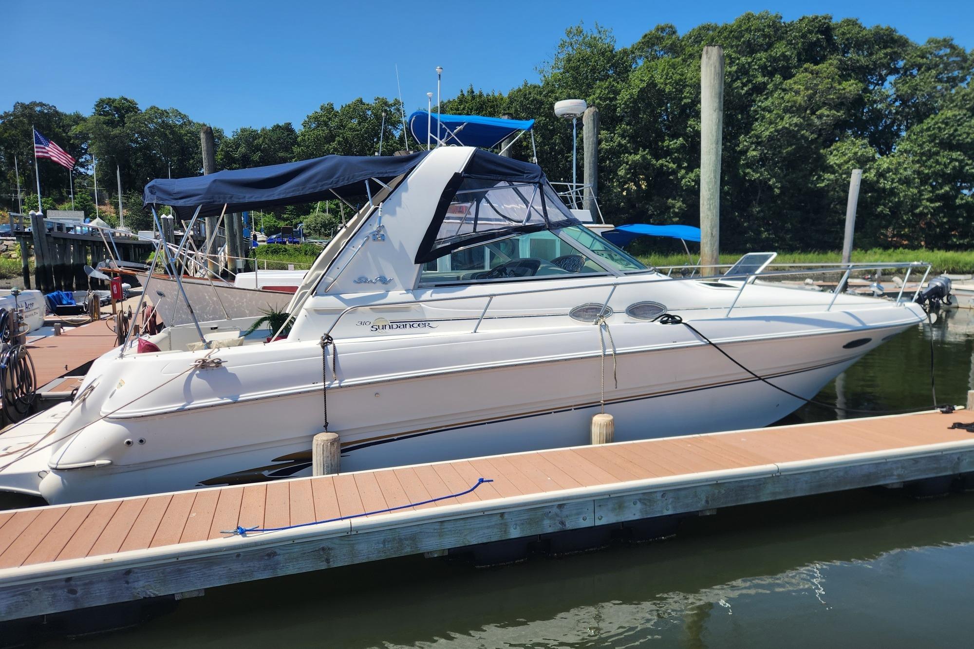 Sea Ray 310 Sundancer 1999 Sea Ray 310 Sundancer docked at a marina, featuring a sleek design and blue canopy.