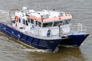 Custom Cat 2 Survey Catamaran Custom 1995 boat navigating through water, featuring a blue and white design with safety equipment.