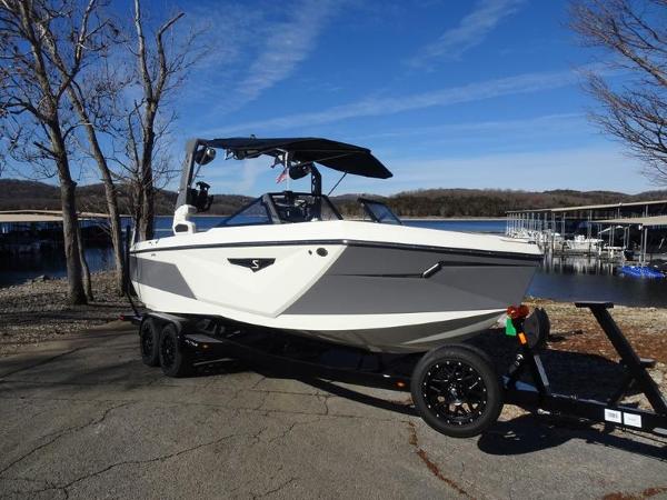 Nautique Super Air Nautique S23 2024 Nautique Super Air Nautique S23 boat on trailer by a lake.