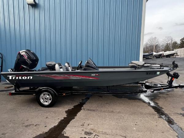 Triton 18 TX 2020 Triton 18 TX fishing boat on trailer, parked outside blue building.