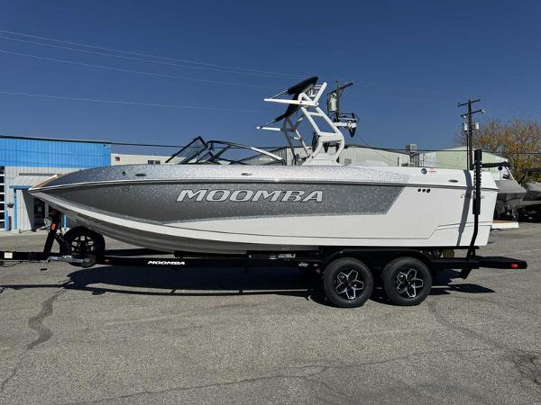 Moomba Mojo 2025 Moomba Mojo boat on trailer, parked outdoors, side view.