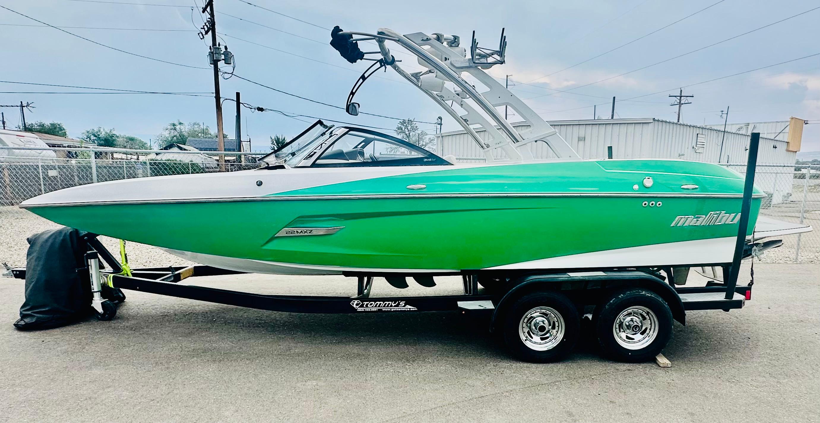 Malibu 22mxz 2012 Malibu 22mxz boat in vibrant green on a trailer, parked outdoors.