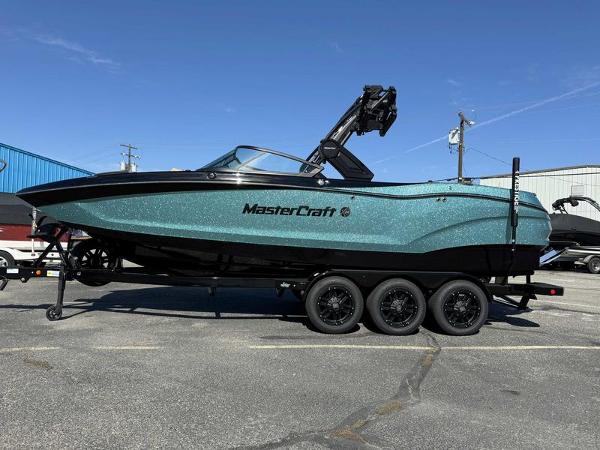 MasterCraft X24 2025 MasterCraft X24 boat on trailer, sparkling teal finish, parked outdoors.