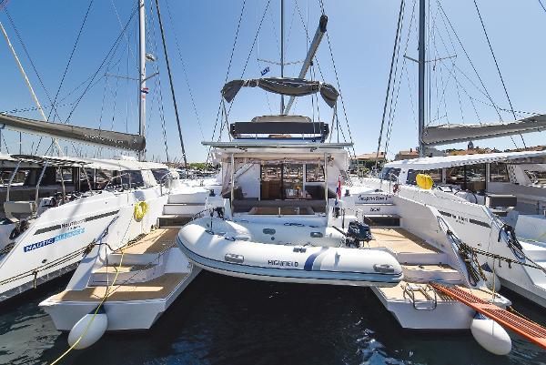 Nautitech OPEN 46 FLY 2018 Nautitech OPEN 46 FLY catamaran docked with inflatable boat, sunny marina setting.