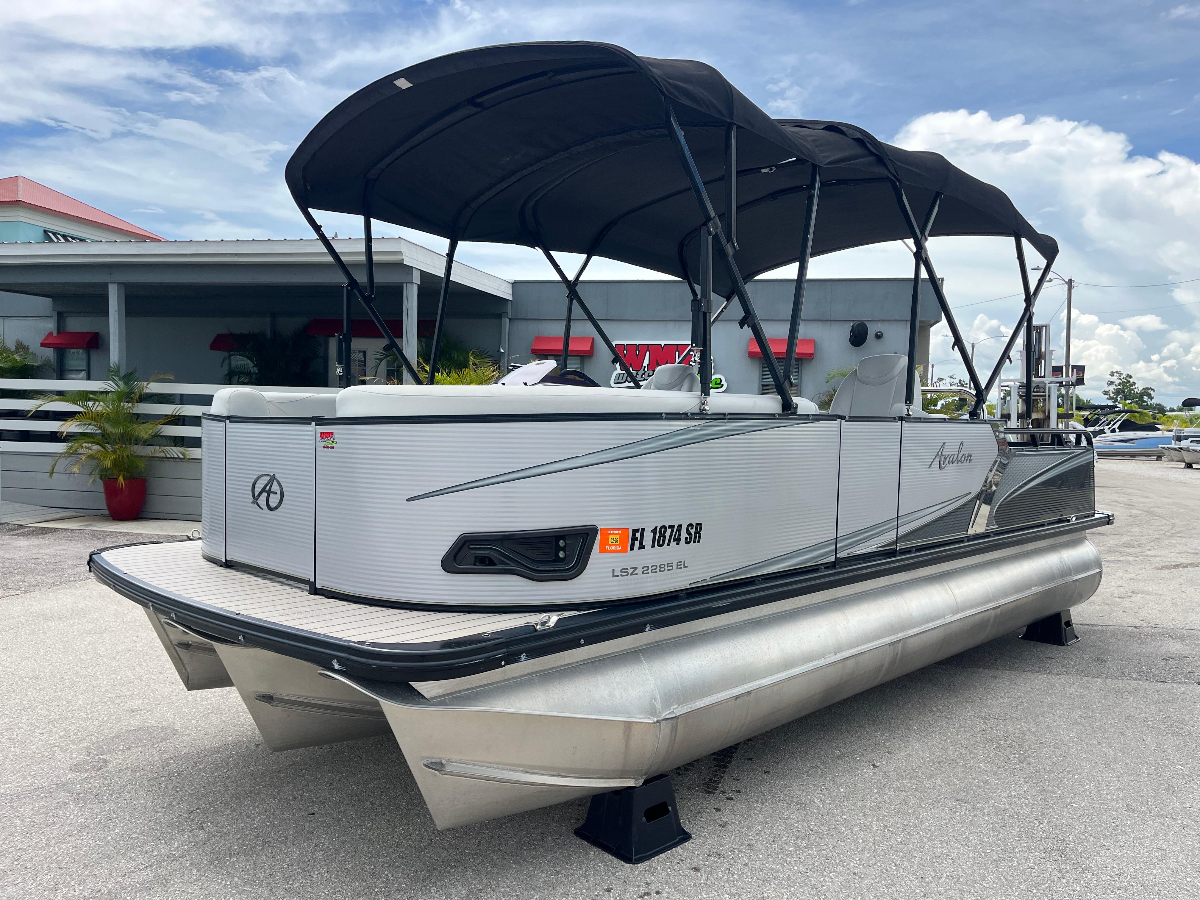 Avalon 2285 LSZ Elite, Tri Toon High Performance 2020 Avalon 2285 LSZ Elite Tri Toon High Performance boat with canopy, parked outdoors.