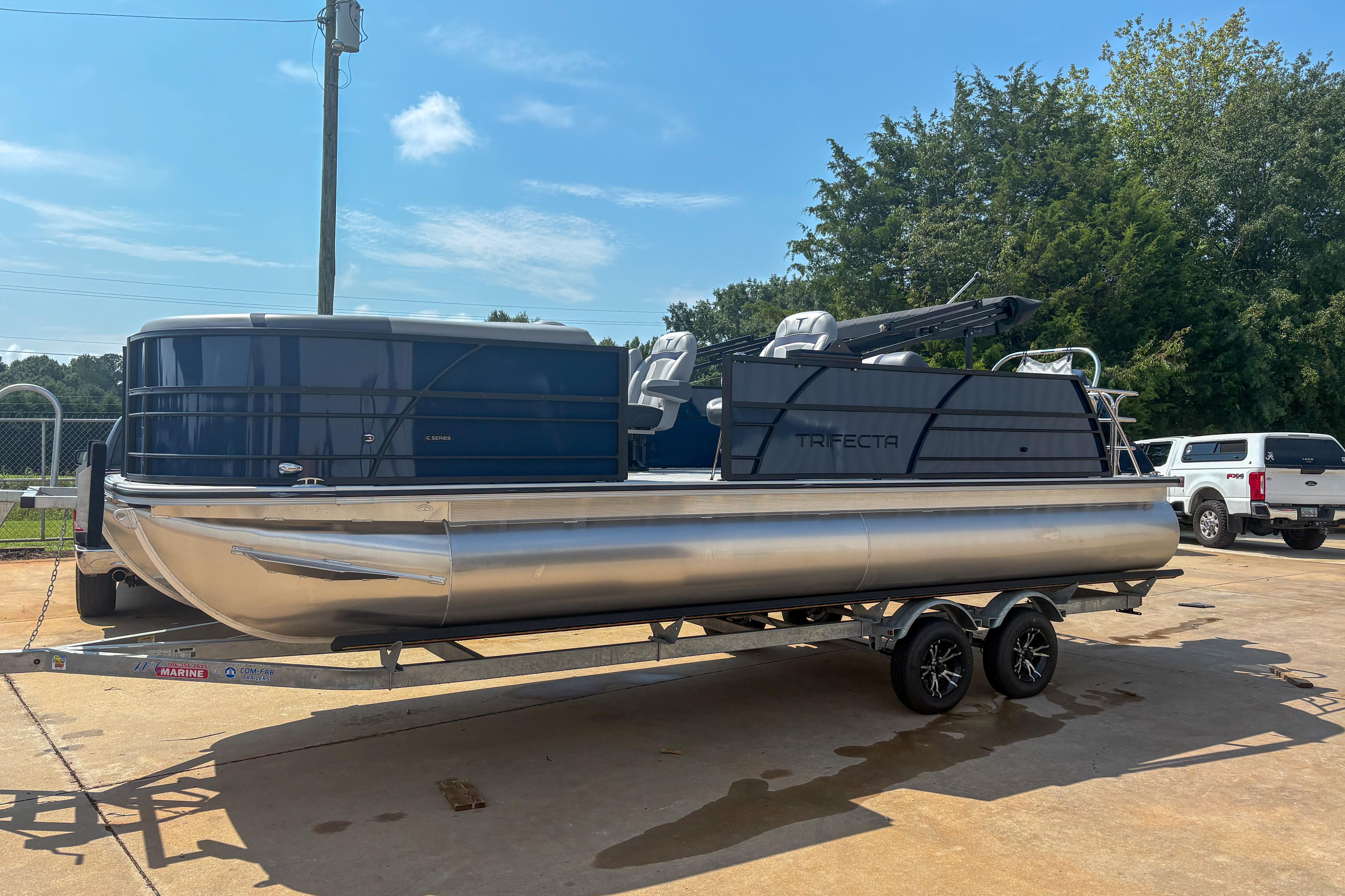 Trifecta 24 UL CS 2025 Trifecta 24 UL CS pontoon boat on trailer, parked outdoors.