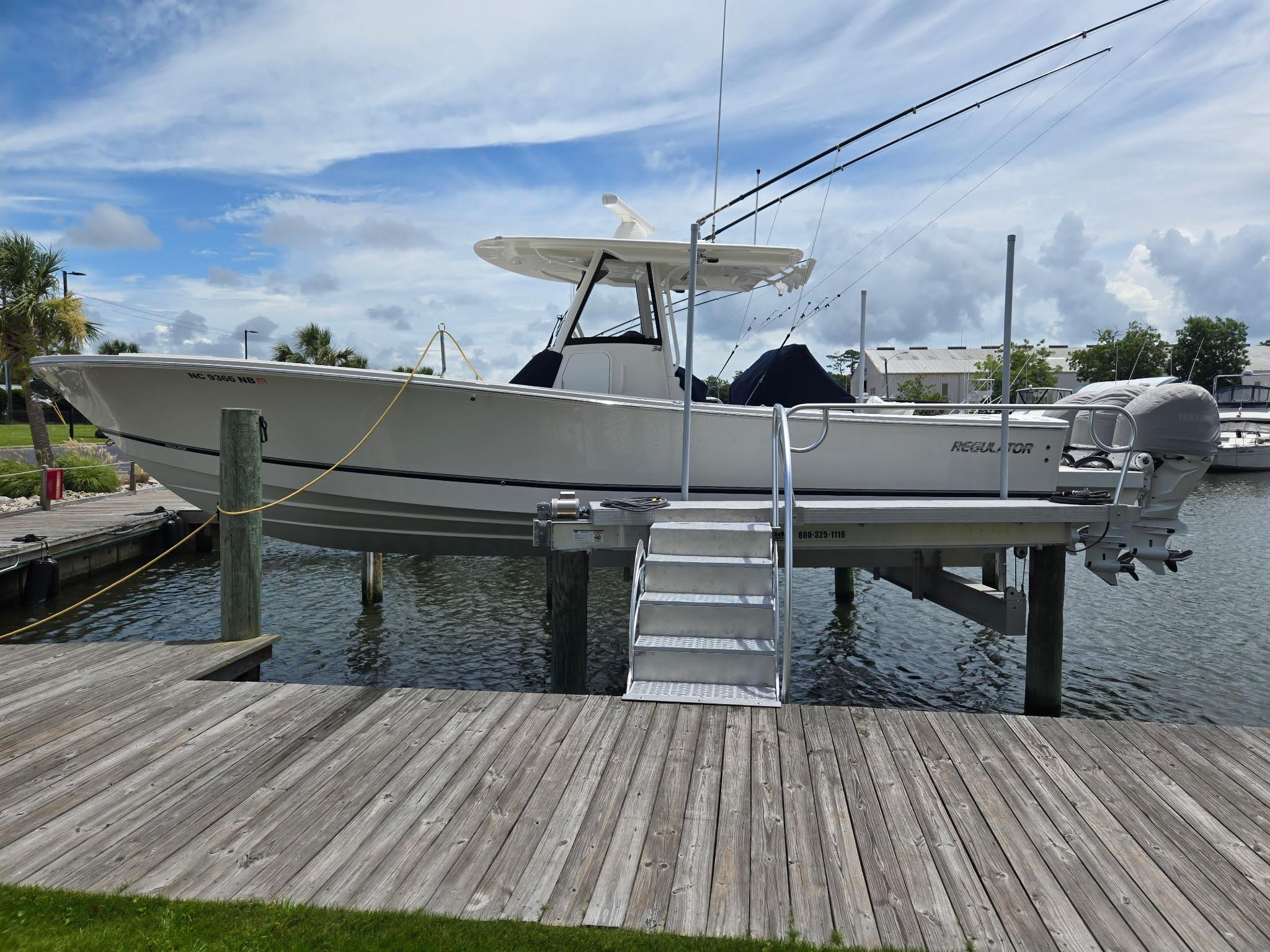 Regulator 34 2023 Regulator 34 boat docked on lift, with fishing rods and clear sky background.