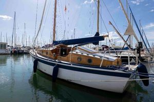 Classic COTRE GRANVILLAIS Classic 1960 COTRE GRANVILLAIS sailboat docked in a marina under clear skies.