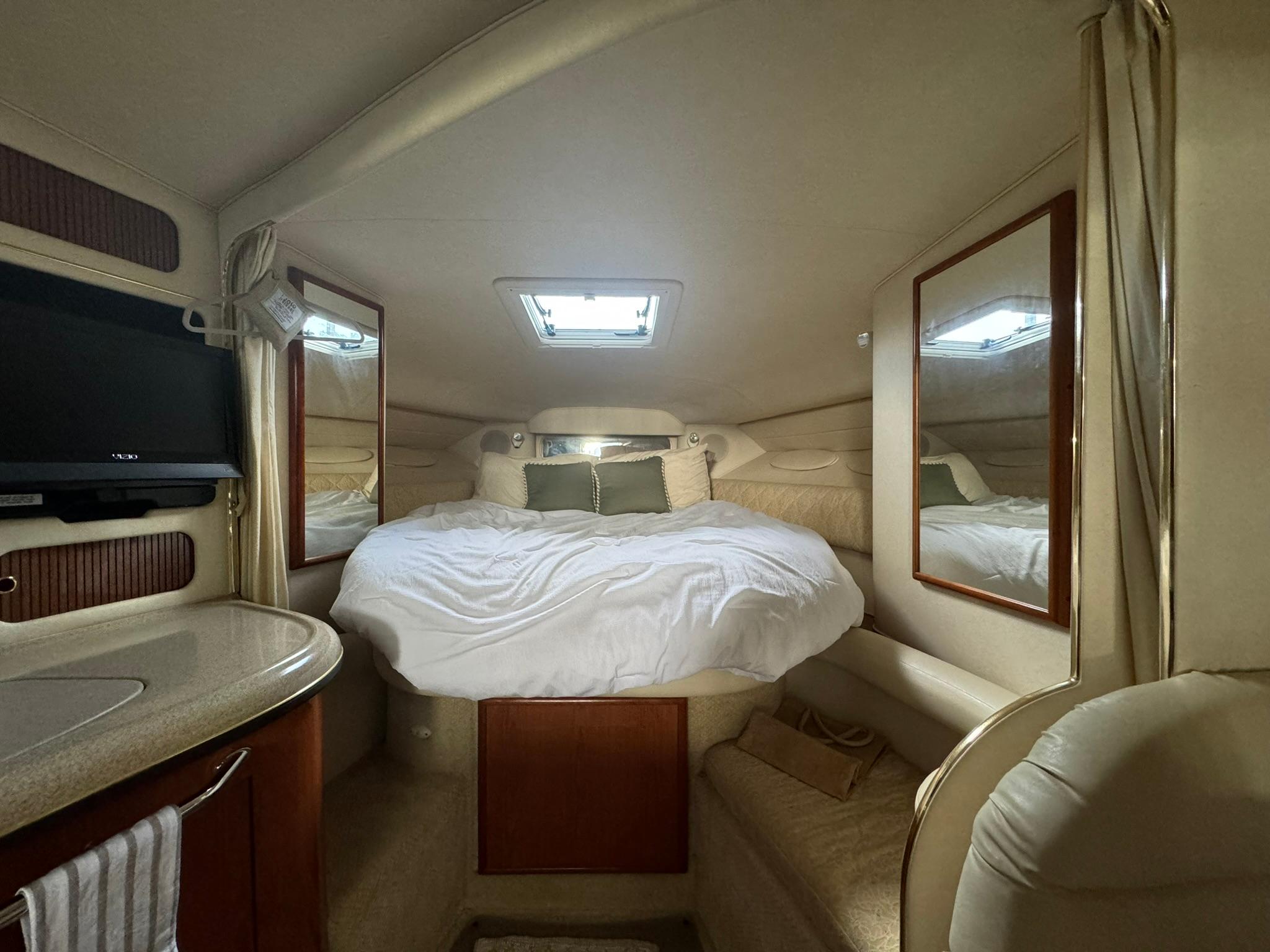 Sea Ray 340 Sundancer Luxurious cabin interior of 2001 Sea Ray 340 Sundancer yacht with cozy bed and mirrors.